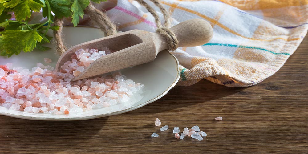 Himalayan salt on a white plate next to orange-checkered napkin.