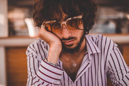 A man leaning his face against his hand and looking tired.