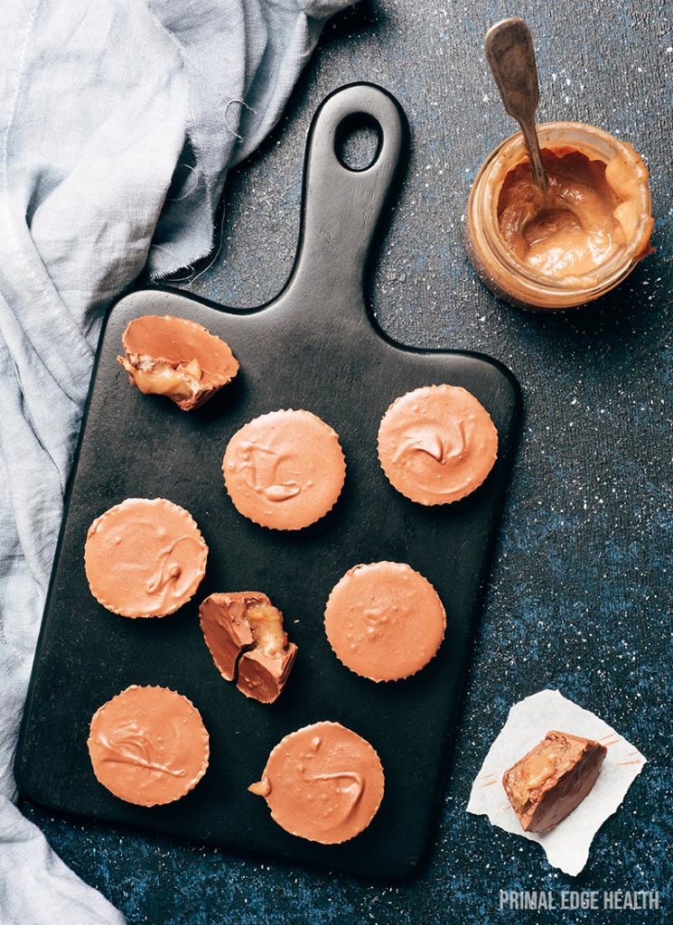 Keto chocolate peanut butter cups on a dark surface.
