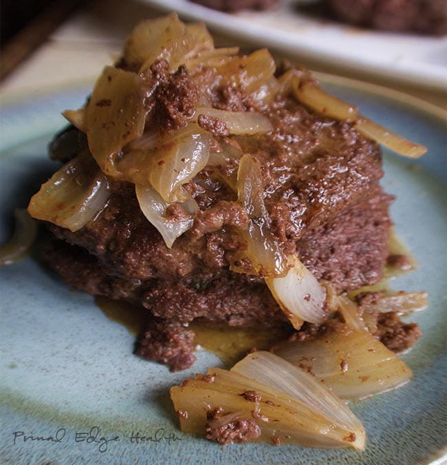 Paleo burgers onion pan sauce on a blue plate.
