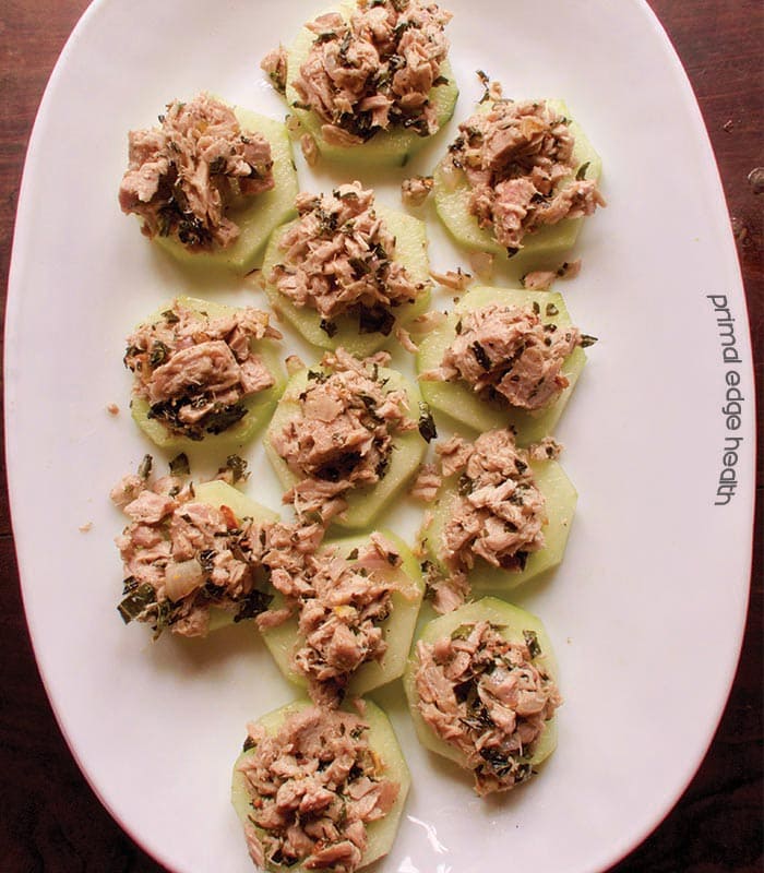 Spicy tuna cucumber bites on a white serving plate.