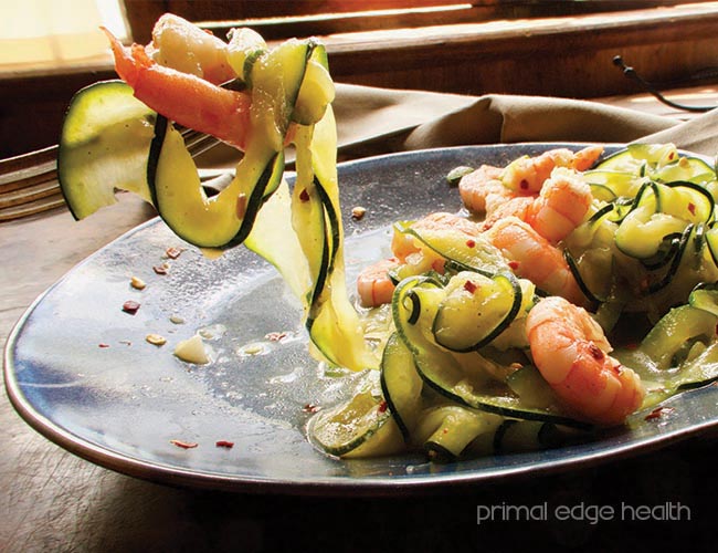 Zoodles shrimp scampi on a blue plate. Primal Edge Health.