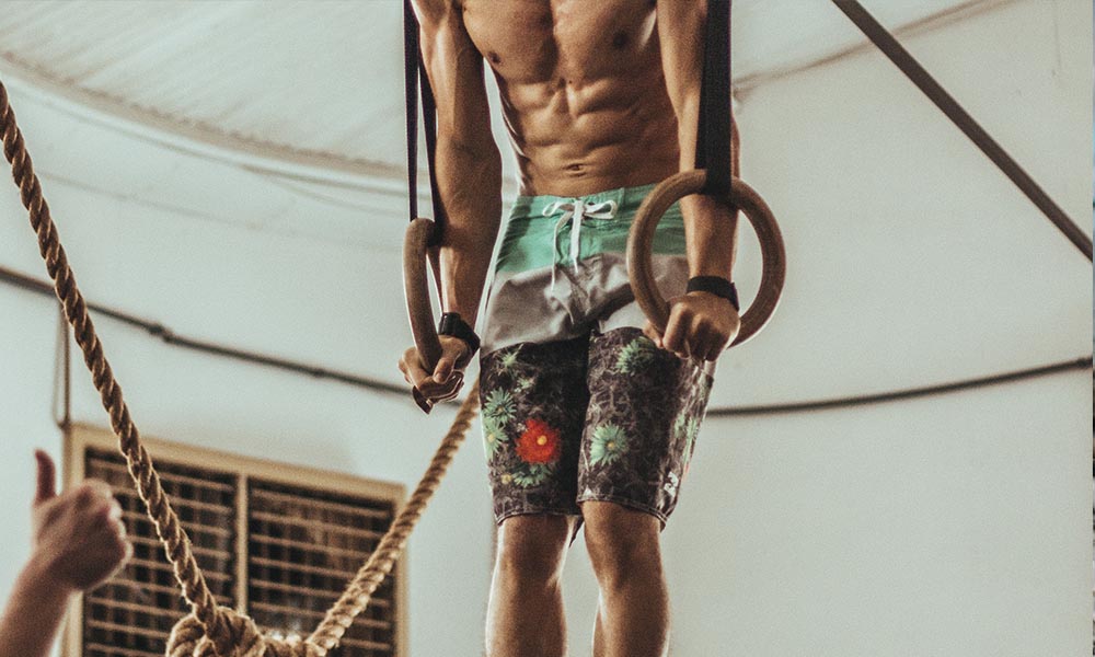 A man doing exercise with a hanging exercise equipment.