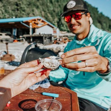 People eating oysters near a body of water.