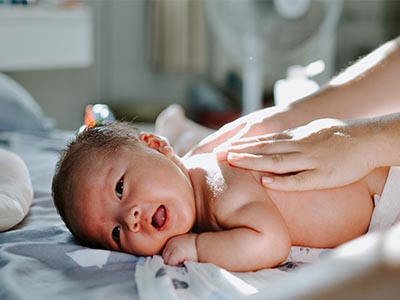 A baby is being massaged using a non-toxic baby lotion recipe in a hospital bed.