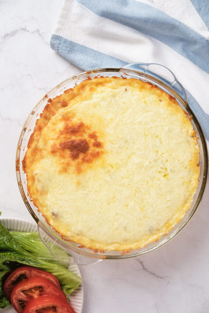 A freshly baked cheeseburger pie in a glass dish.