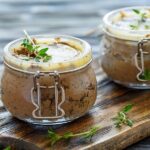 Two jars filled with a mixture of chocolate and thyme combined with classic beef liver pate.