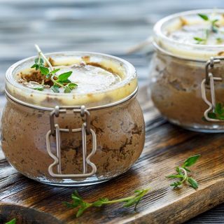 Two jars filled with a mixture of chocolate and thyme combined with classic beef liver pate.
