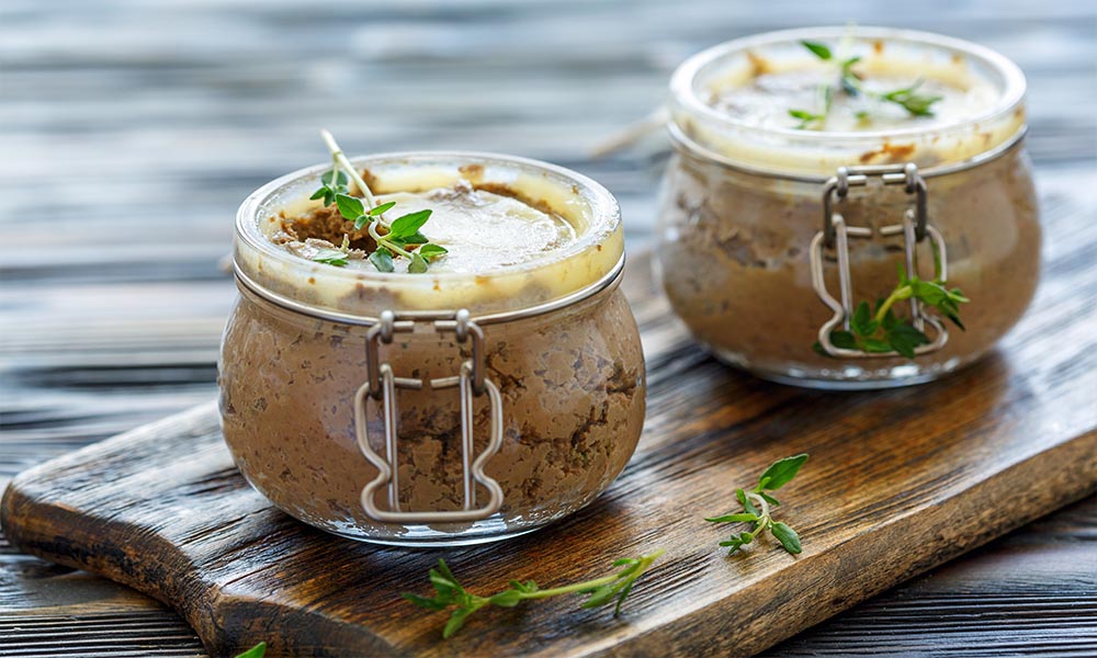 Two jars filled with a mixture of chocolate and thyme combined with classic beef liver pate.
