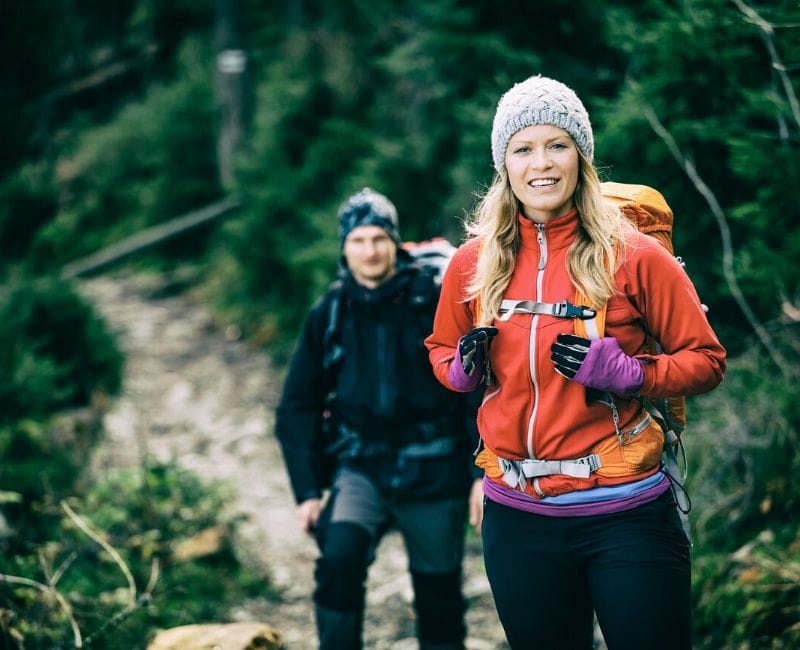 A woman and a man hiking in the woods.