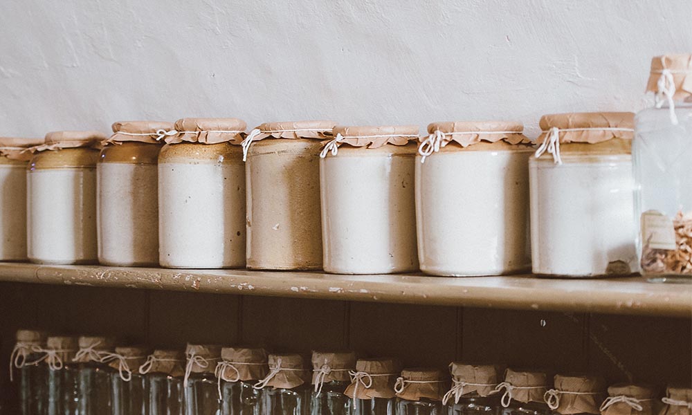 A row of keto pantry staples jars lined up on a shelf.