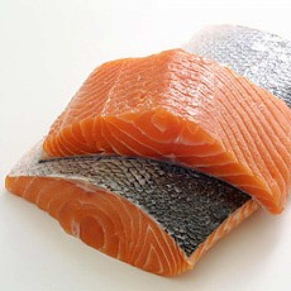 Two pieces of salmon on a white surface.