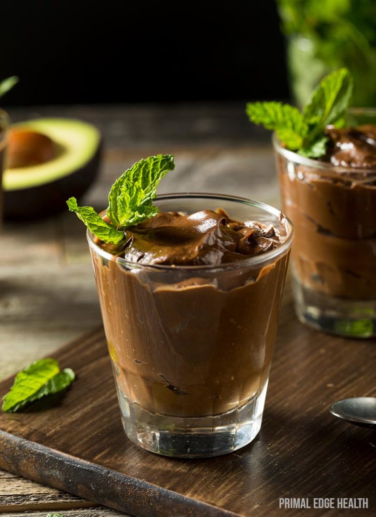 Two servings of keto chocolate avocado pudding with garnish.
