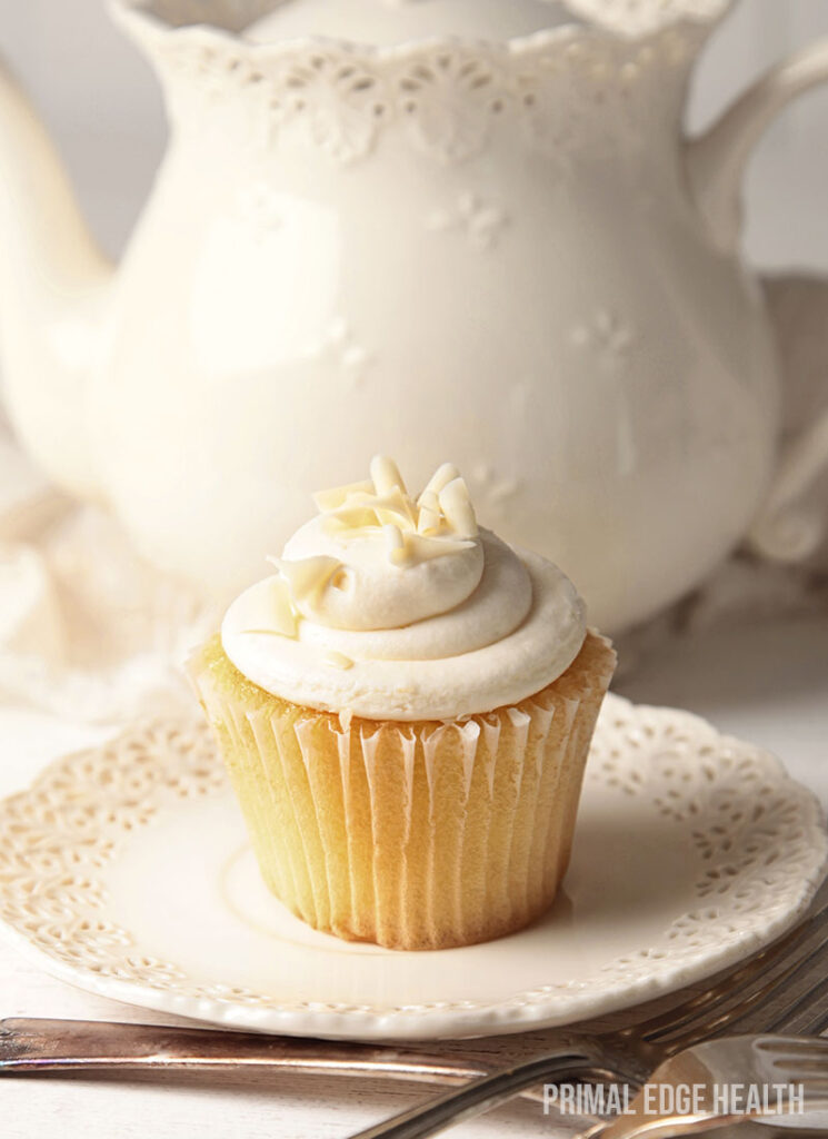 a piece of vanilla cupcake on a textured white plate.