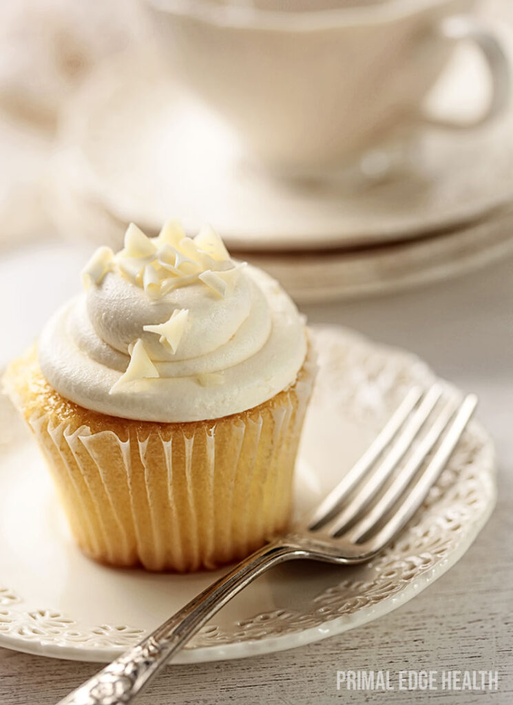 Keto vanilla cupcake served on a white plate with a fork.