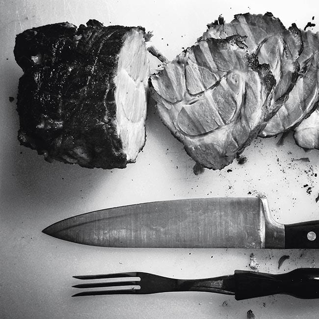 A knife and fork next to a piece of meat.