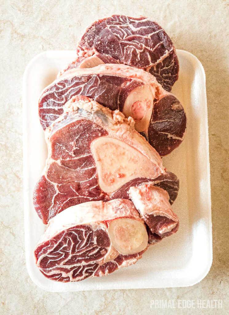 Uncooked beef shank on white tray.