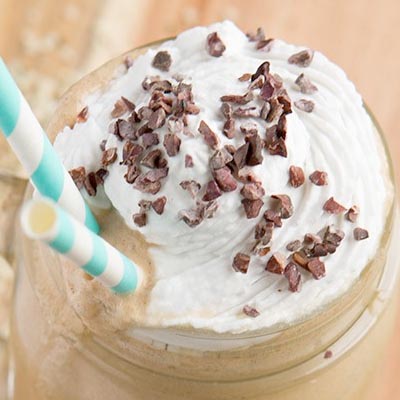 A mason jar with smoothie topped with cacao nibs.