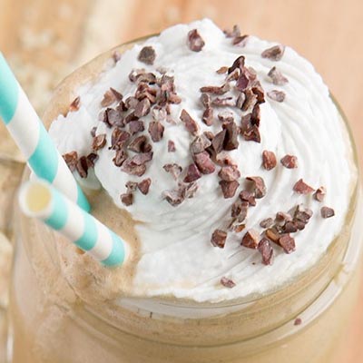 A glass with smoothie topped with cacao nibs.