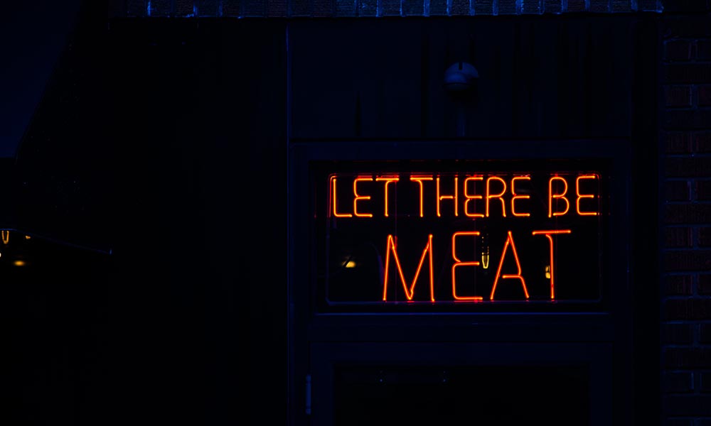 Orange neon lights displaying let there be meat