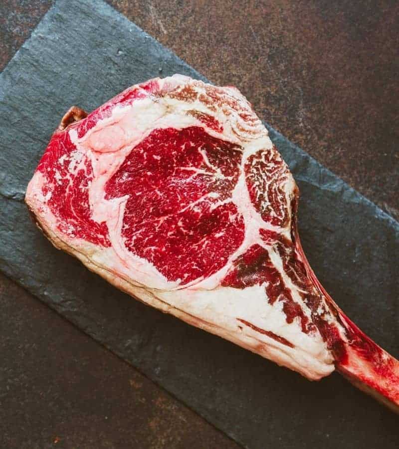 A piece of steak on a rustic slate table.
