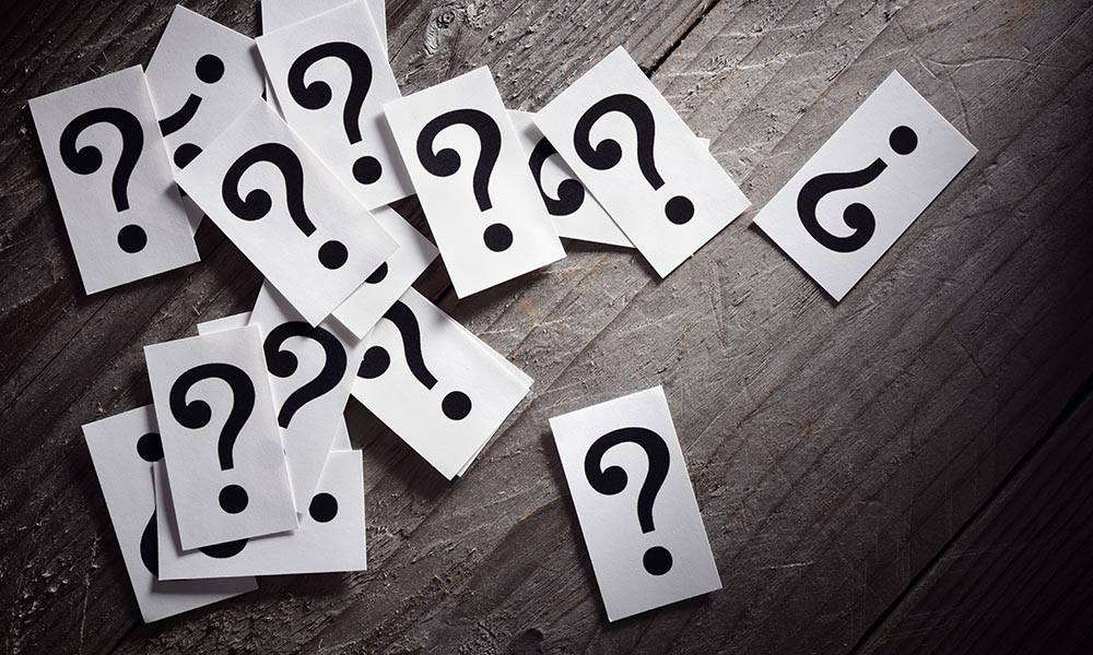 Question marks scattered on a wooden surface.