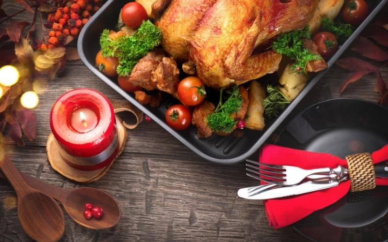 Roast chicken with vegetables on a table set with a lit candle.