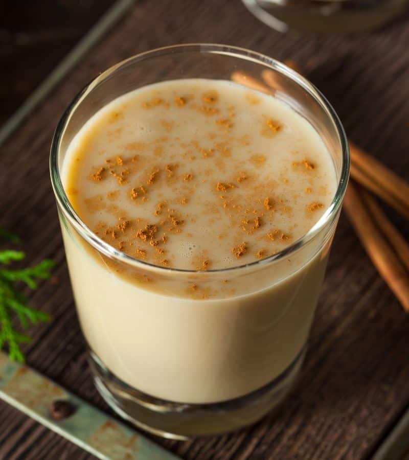 A glass of eggnog recipe on a wooden surface.