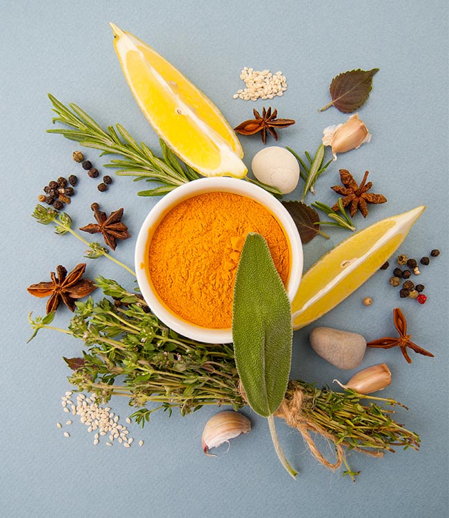 Tumeric powder and herbs on a blue background.