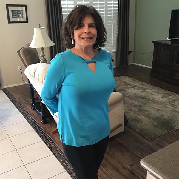 A woman in a blue shirt standing in a living room.