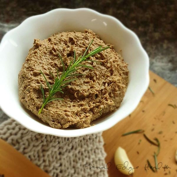 A bowl of liver pate with a sprig of rosemary.