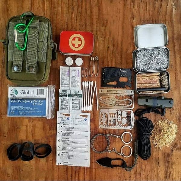 A survival kit laid out on a wooden table.