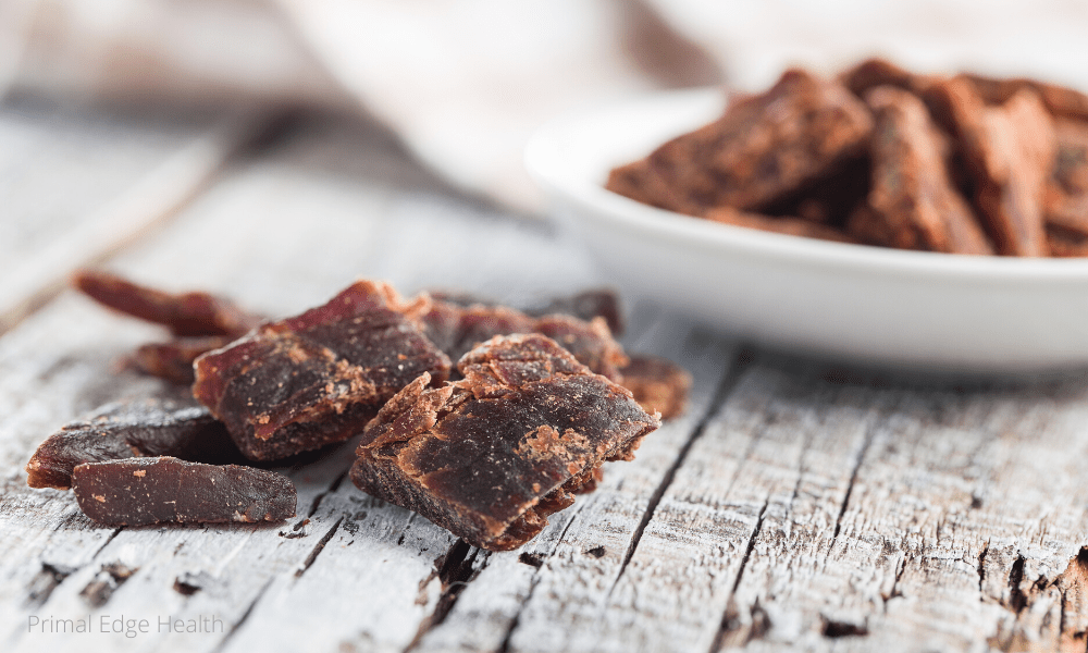 Brown chunks of food in on a white plate and on a wooden surface.