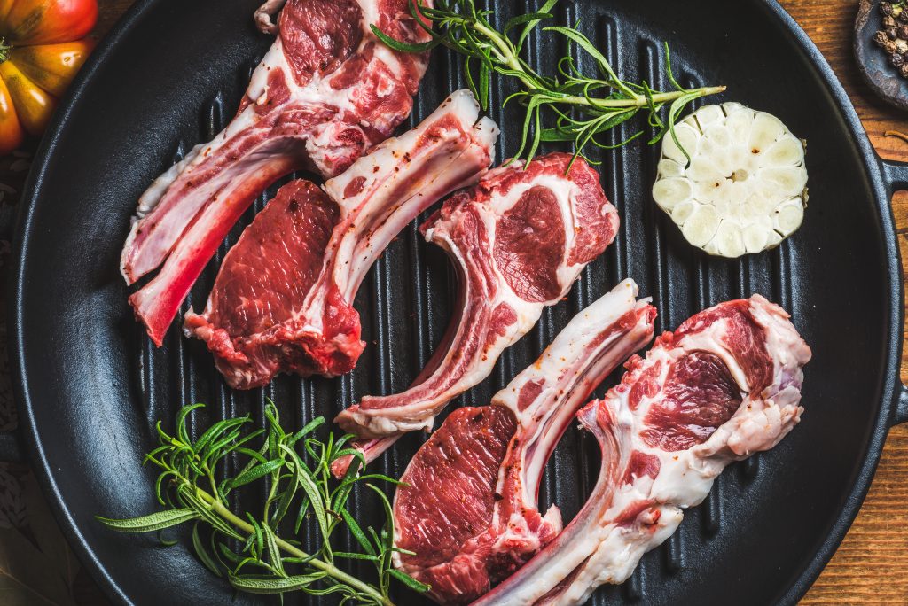 Grilled lamb ribs on a grill with herbs and spices.