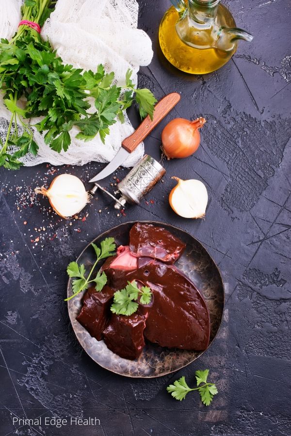 Grass-fed liver on a plate with different spices on a black background.