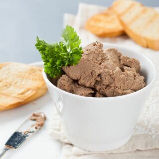 Carnivore chicken liver pate in a bowl next to slices of bread.