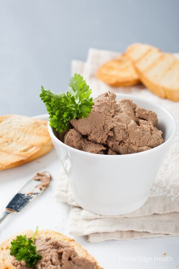 Carnivore chicken liver pate in a bowl next to slices of bread.