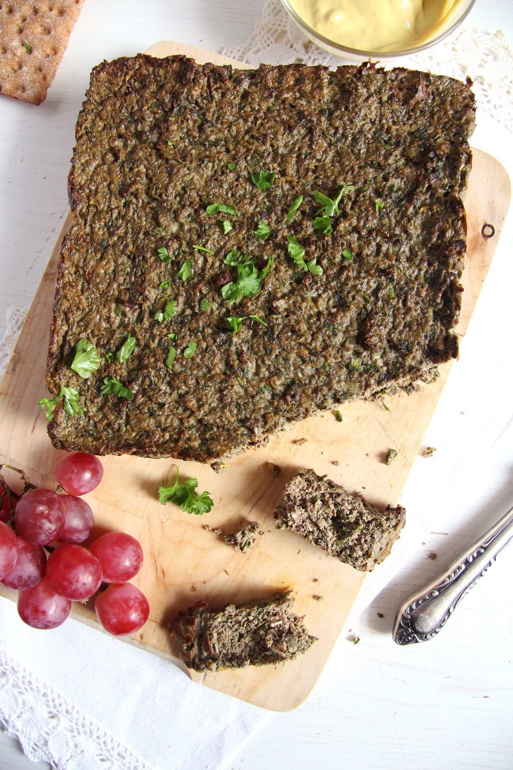 An easy liver pate recipe on a cutting board with grapes on it.