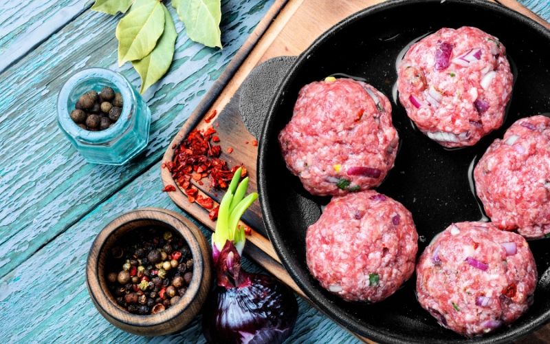 Five meat balls in a pan.