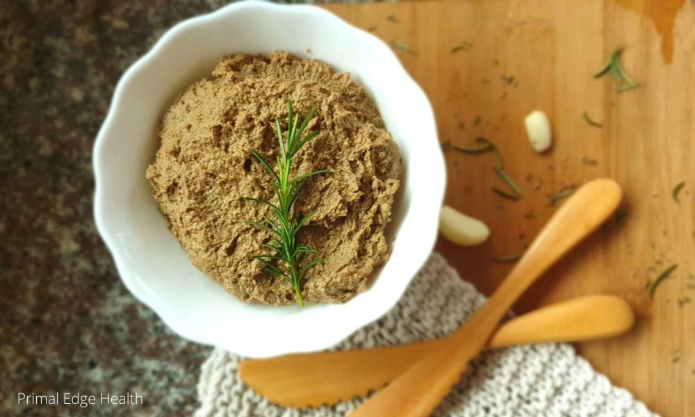 A dairy-free liver pate served in a white bowl with a sprig of rosemary.