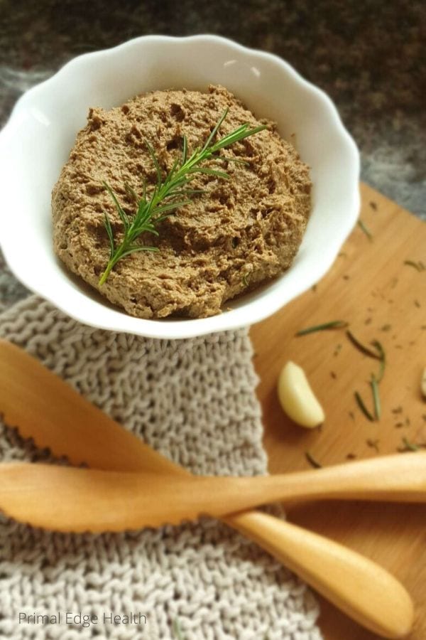 A white bowl with dairy-free liver pate on a wooden board.