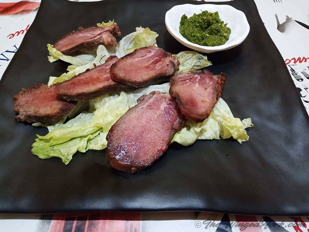 Salt-cured tongue on a black plate.
