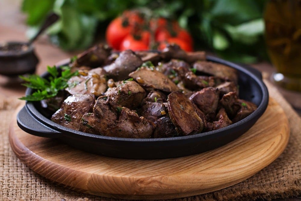 Instant pot chicken liver with onions on a wooden circular board.