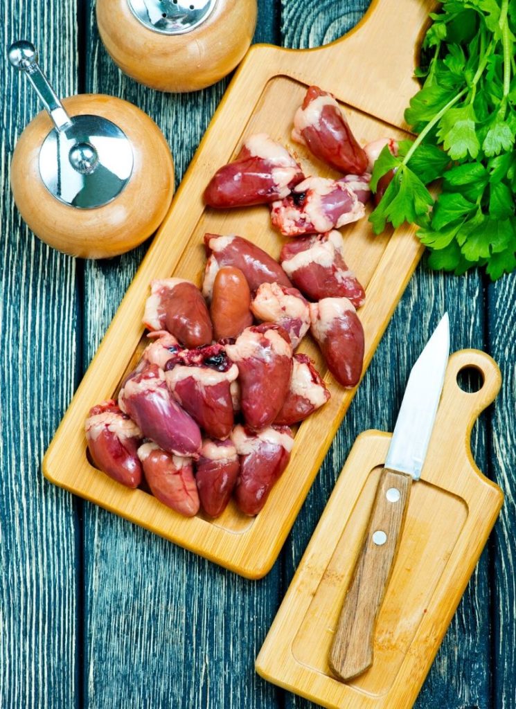 A wooden tray containing organ meat on a wooden surface.