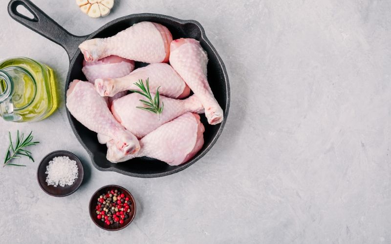 Chicken legs in a frying pan on a gray background.