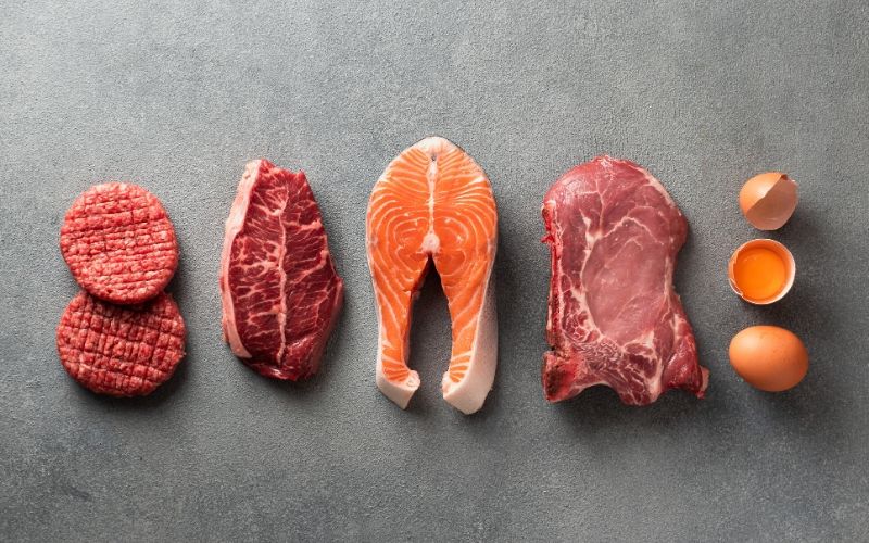 Various meat and eggs on a grey backgroud.