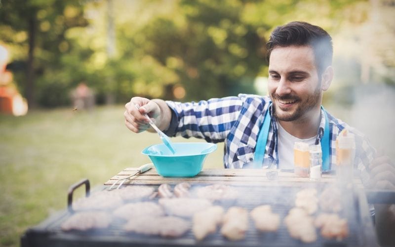 A smiling man in front of a grill.