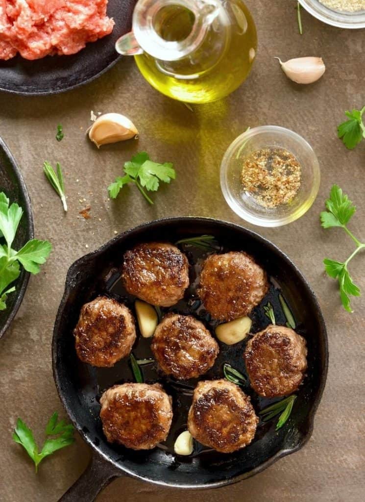 Meatballs in a skillet with some herbs.