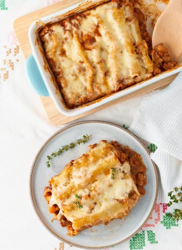 Two servings of lasagna on a white surface.