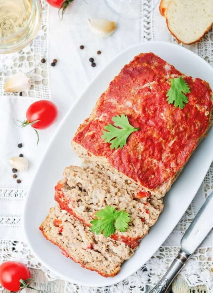 A serving of meat with garnish on a white plate.
